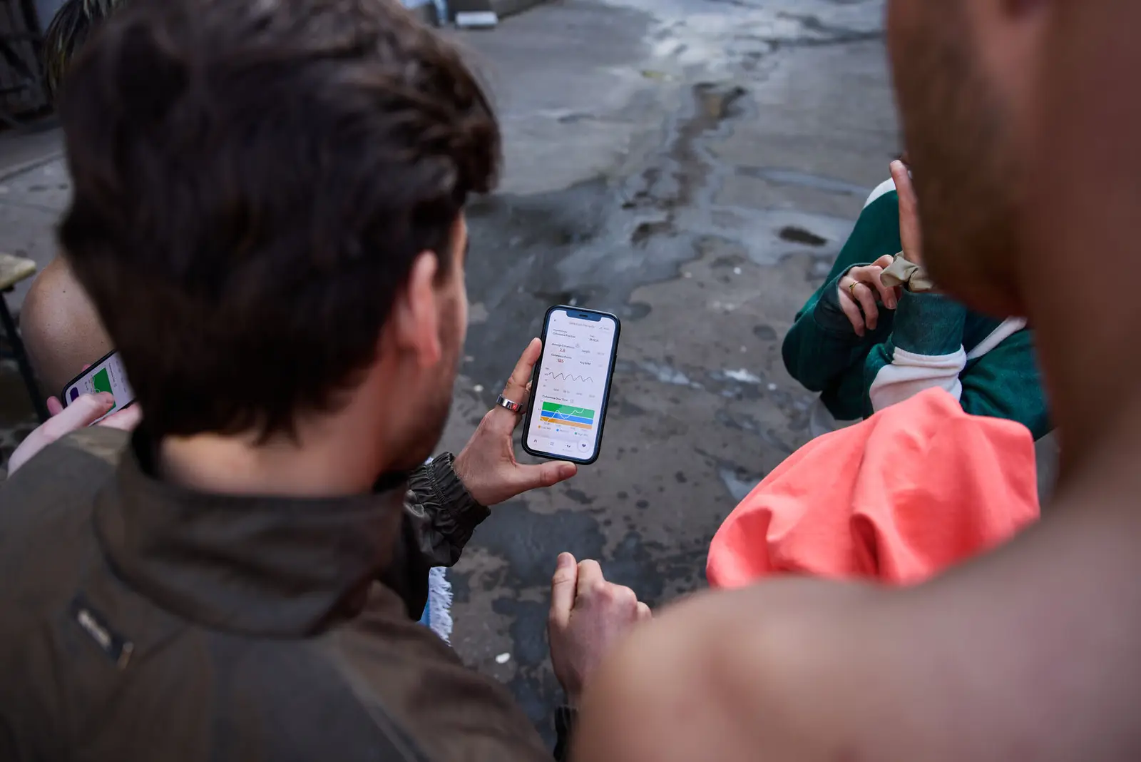 Two people outdoors reading data on a phone.