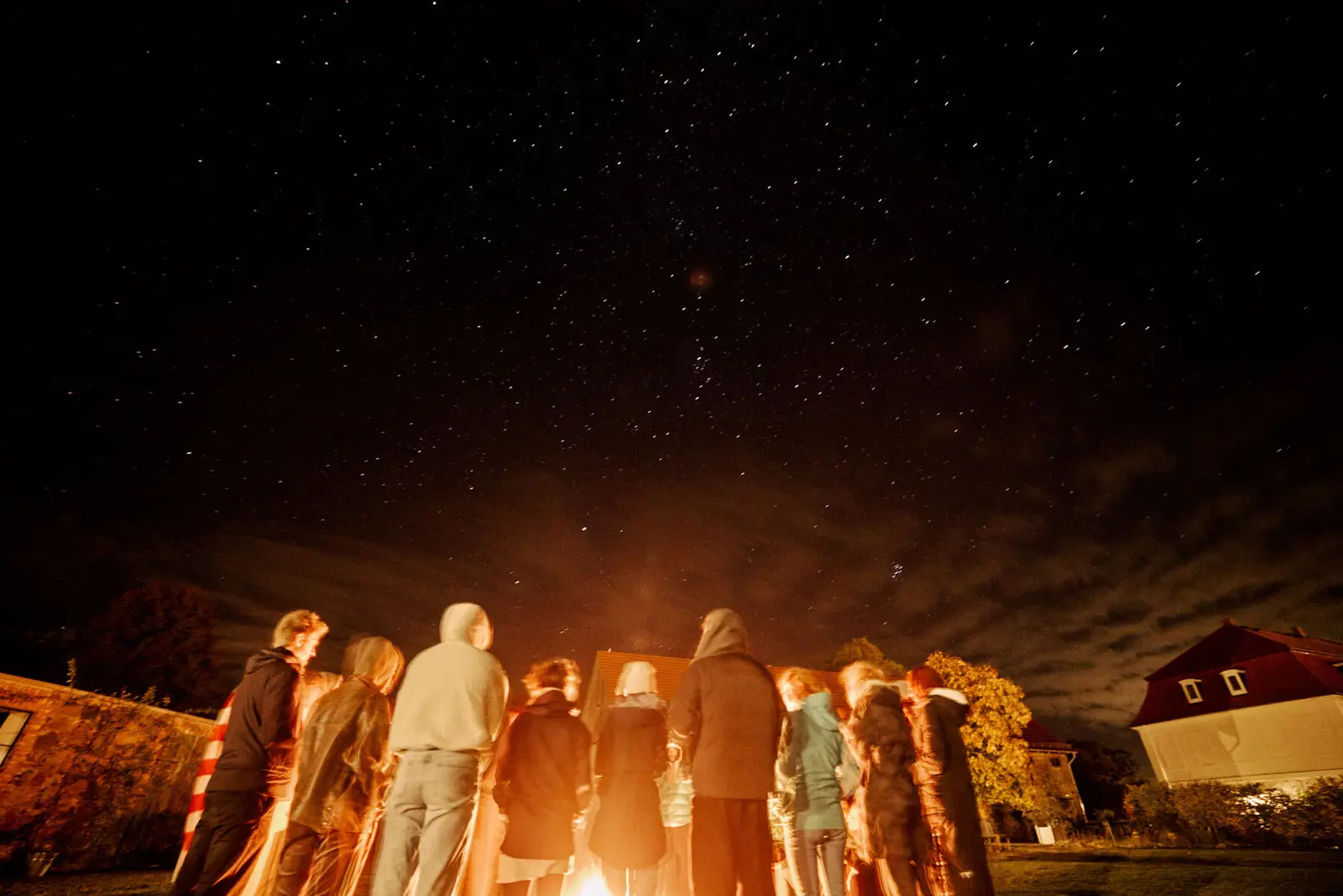 A group gathered around a fire under a night sky.