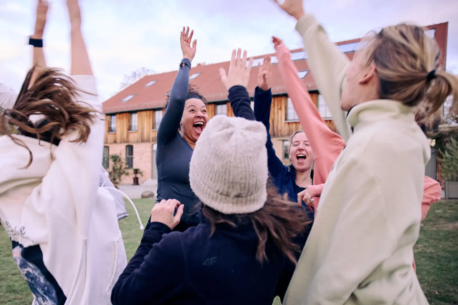 A group outdoors with their arms up, laughing.