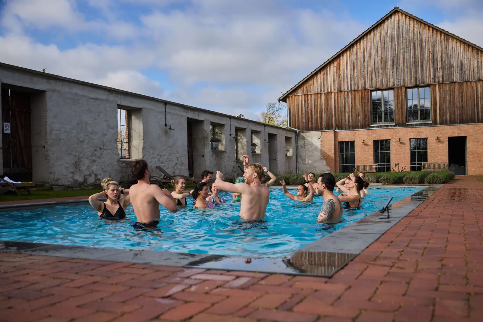 A group together in an outdoor pool beside a barn.